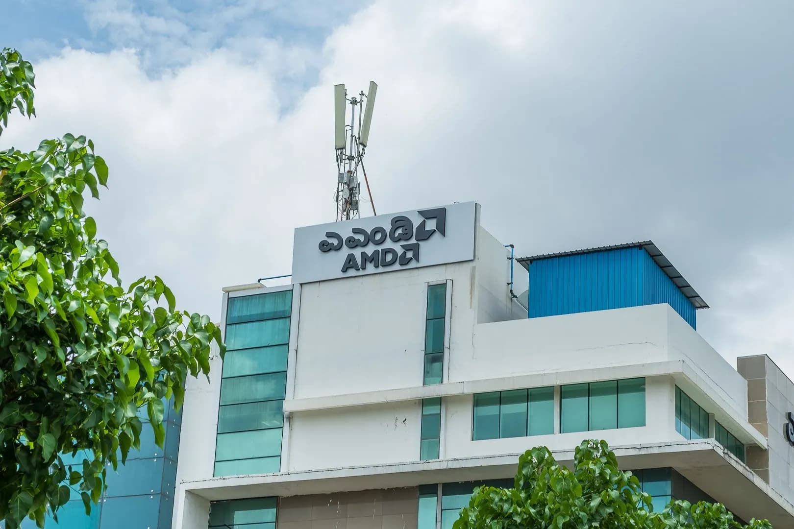AMD rooftop sign in Kannada and English on a white office block
