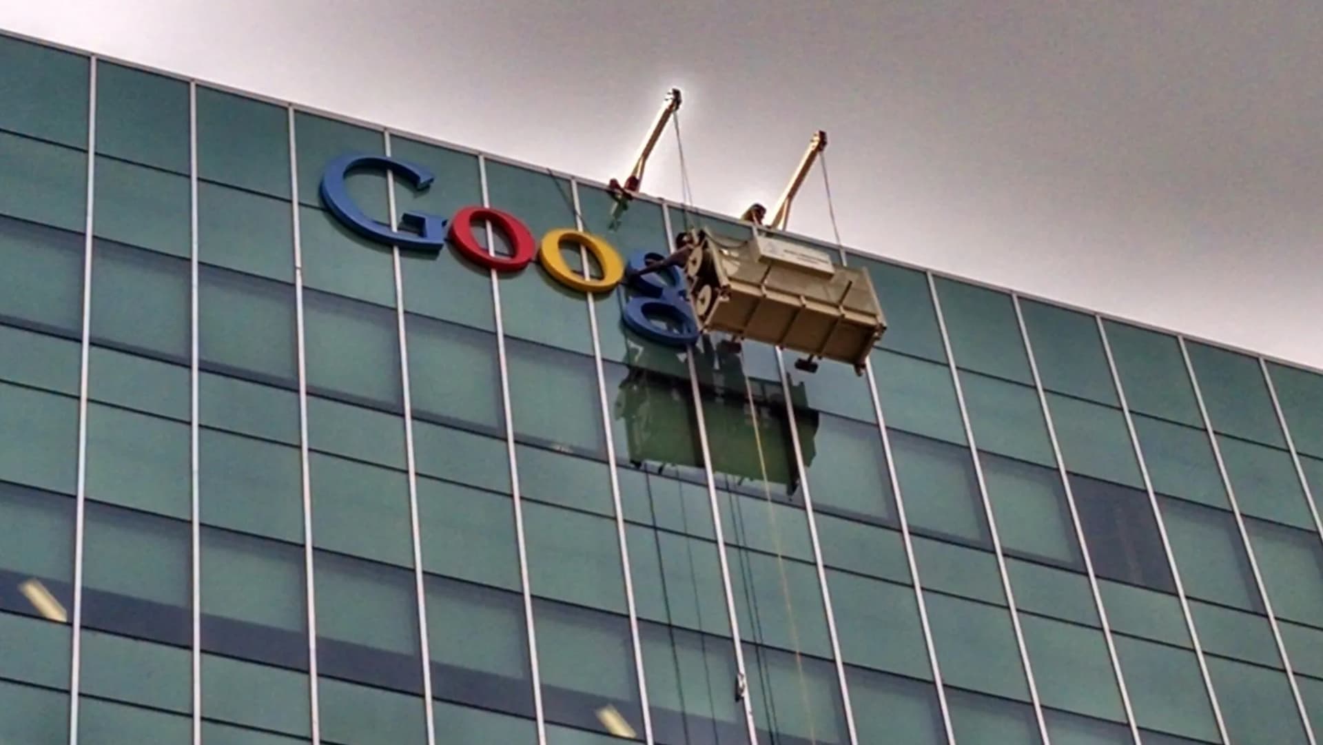 Installers in a gondola fixing the Google letters to a glass office facade