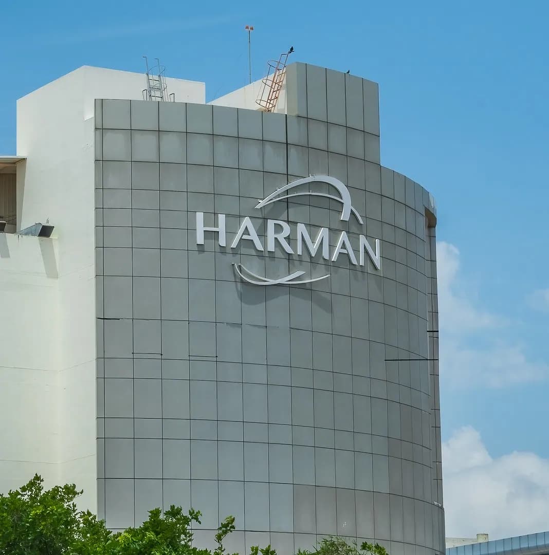 HARMAN letters on the curved facade of an office tower against a blue sky