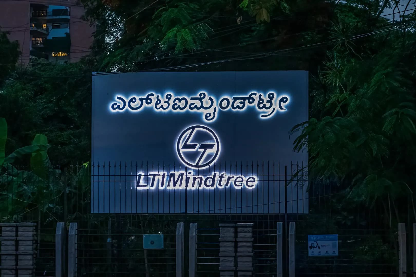 LTIMindtree boundary sign lit at dusk, Kannada and English letters glowing