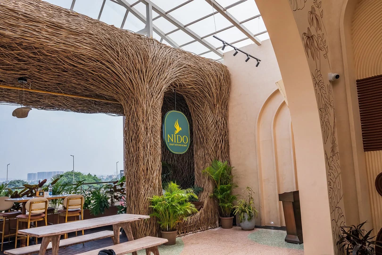 Rooftop terrace at NIDO with a woven cane arch and the hanging sign