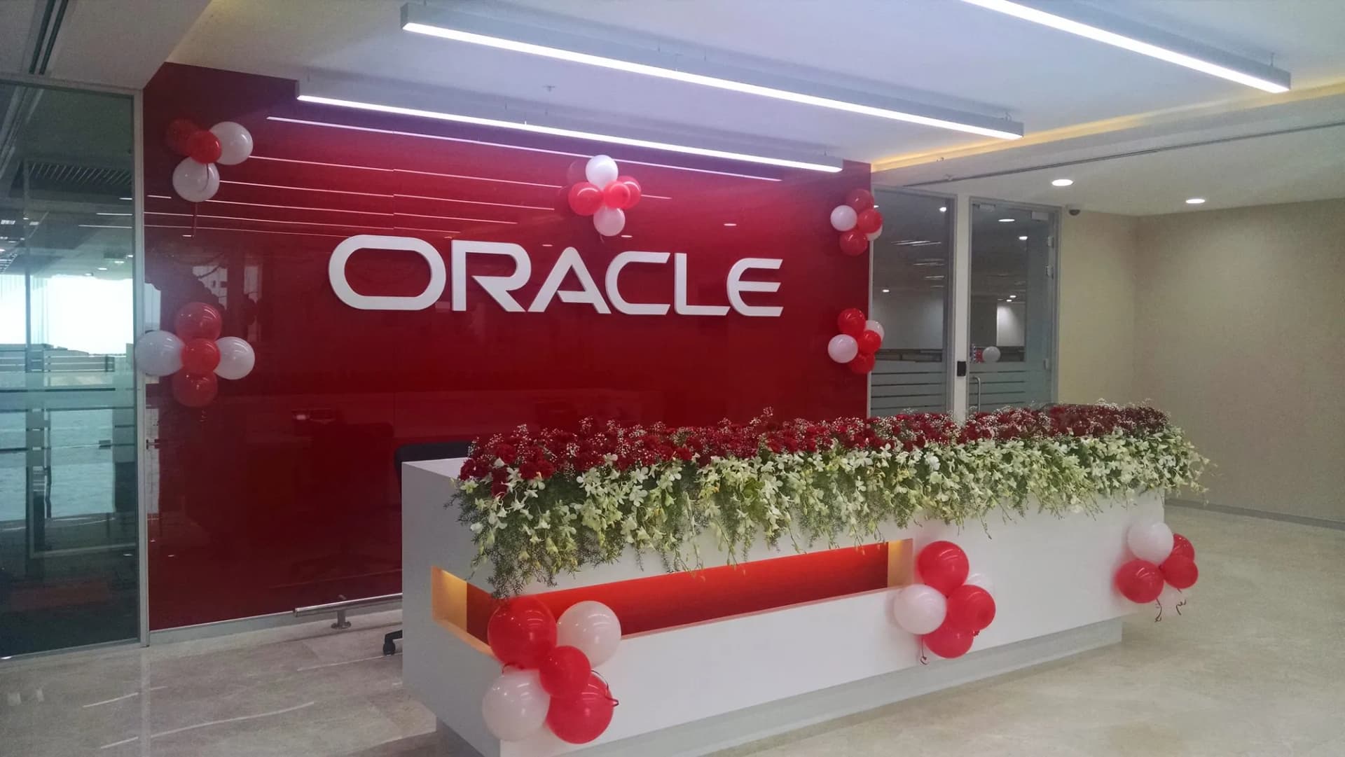 White ORACLE letters on a red reception wall, decorated for the office opening