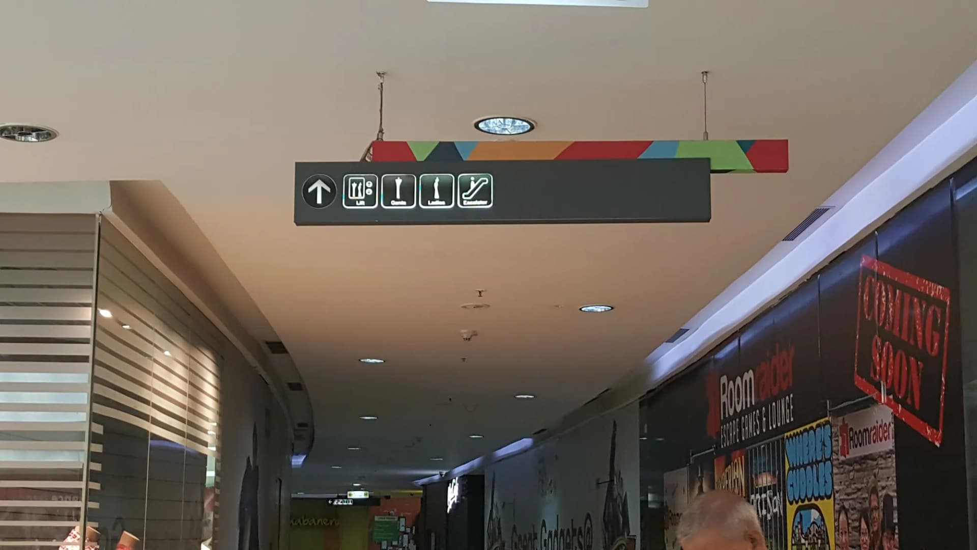 Hanging directional sign with service pictograms in a mall corridor