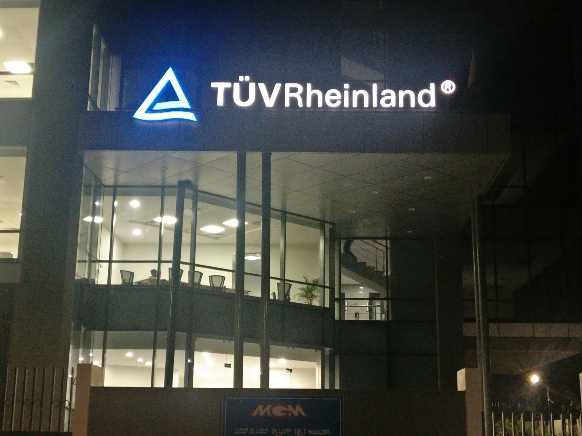 TUV Rheinland letters lit at night above an office entrance canopy