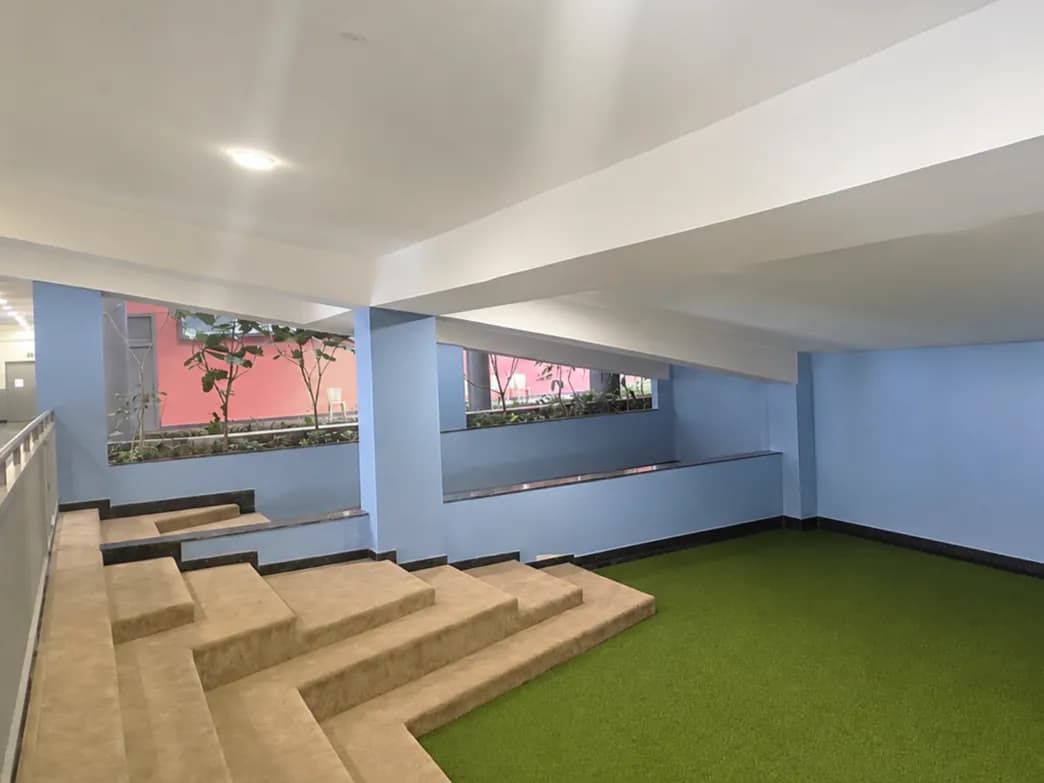 The play area before: plain blue walls, bare pillars, carpeted steps and green turf