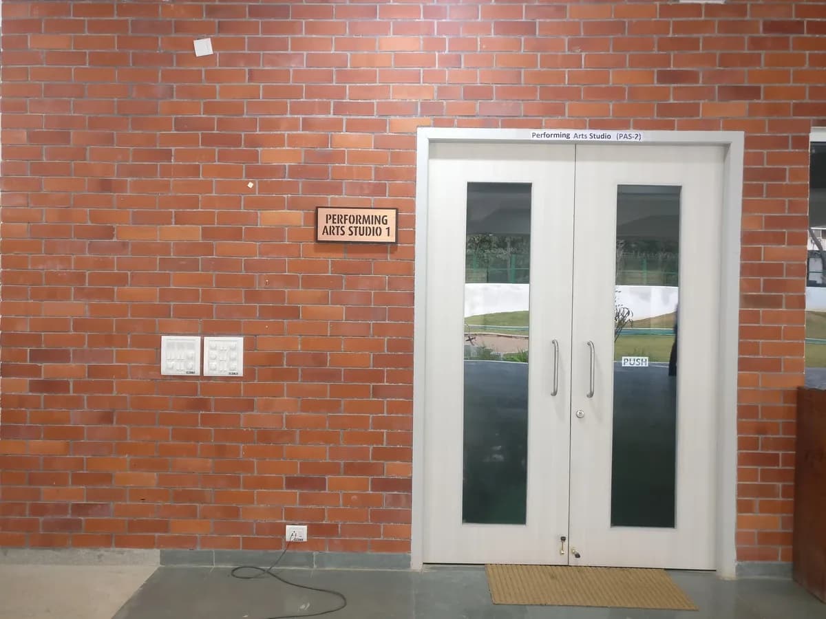 Performing Arts Studio 1 room-identification plaque mounted beside a doorway on a brick wall