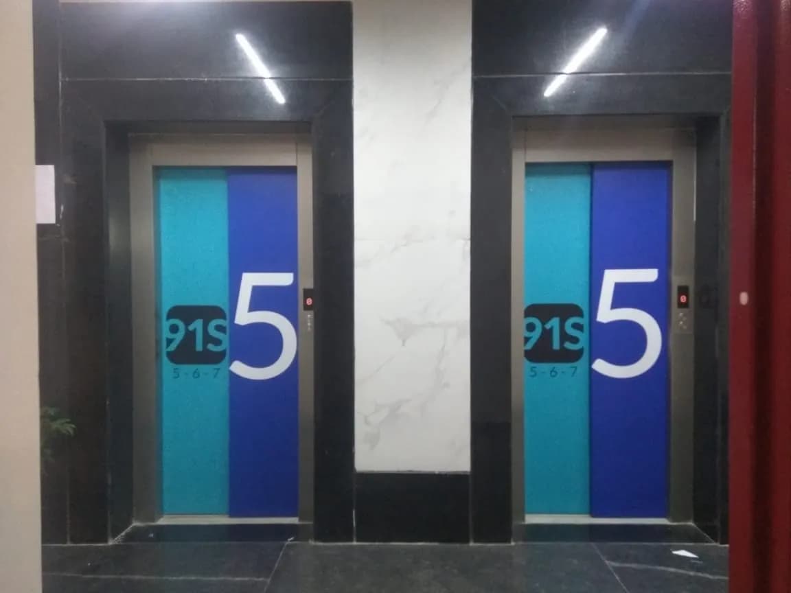 Lift doors at 91springboard wrapped in teal and blue graphics with a large floor number 5