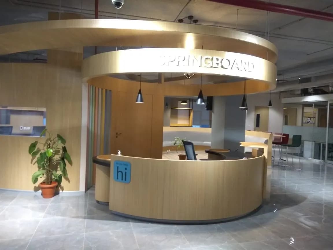 91springboard co-working reception: round timber desk under a curved canopy with the brand letters