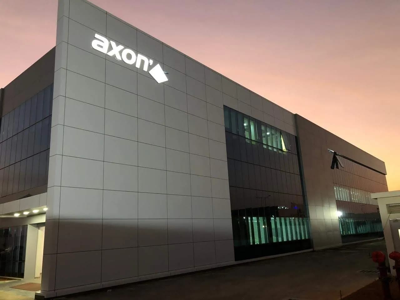 Axon logo letters on a grey panel factory facade at sunset