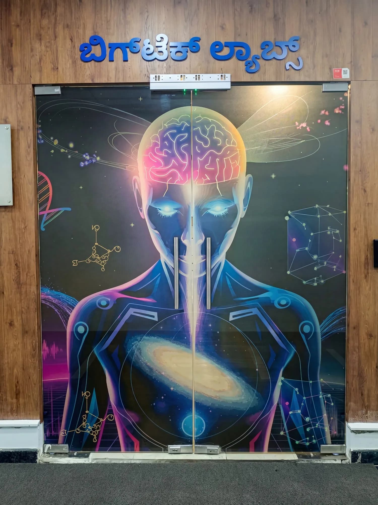 Glass double door at BigTech Labs printed with a brain-and-cosmos illustration