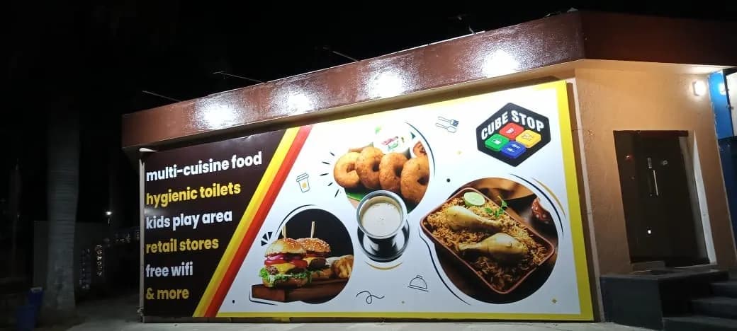 Printed food-court graphic wrapping a small building at Cube Stop, lit at night