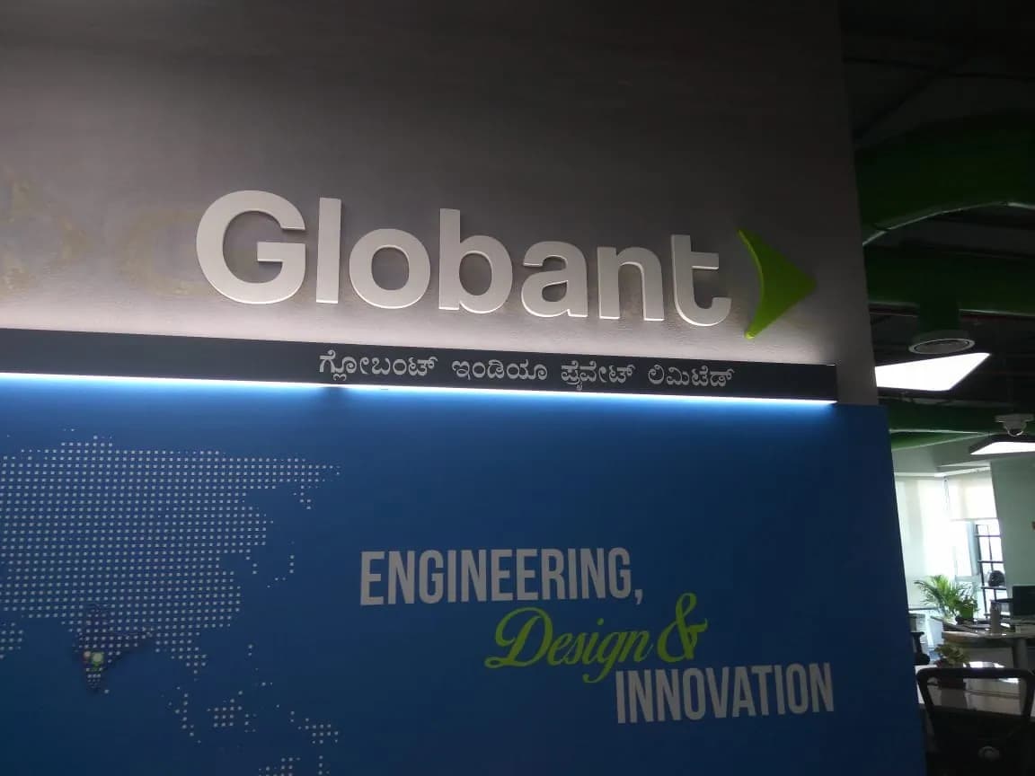 Lit GLOBANT letters with the Kannada name over a blue world-map wall