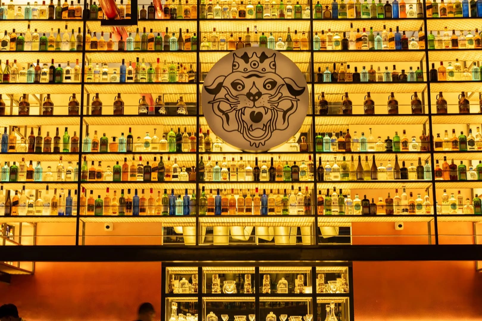 Ironhill bar: lit bottle wall with a round tiger emblem at its centre