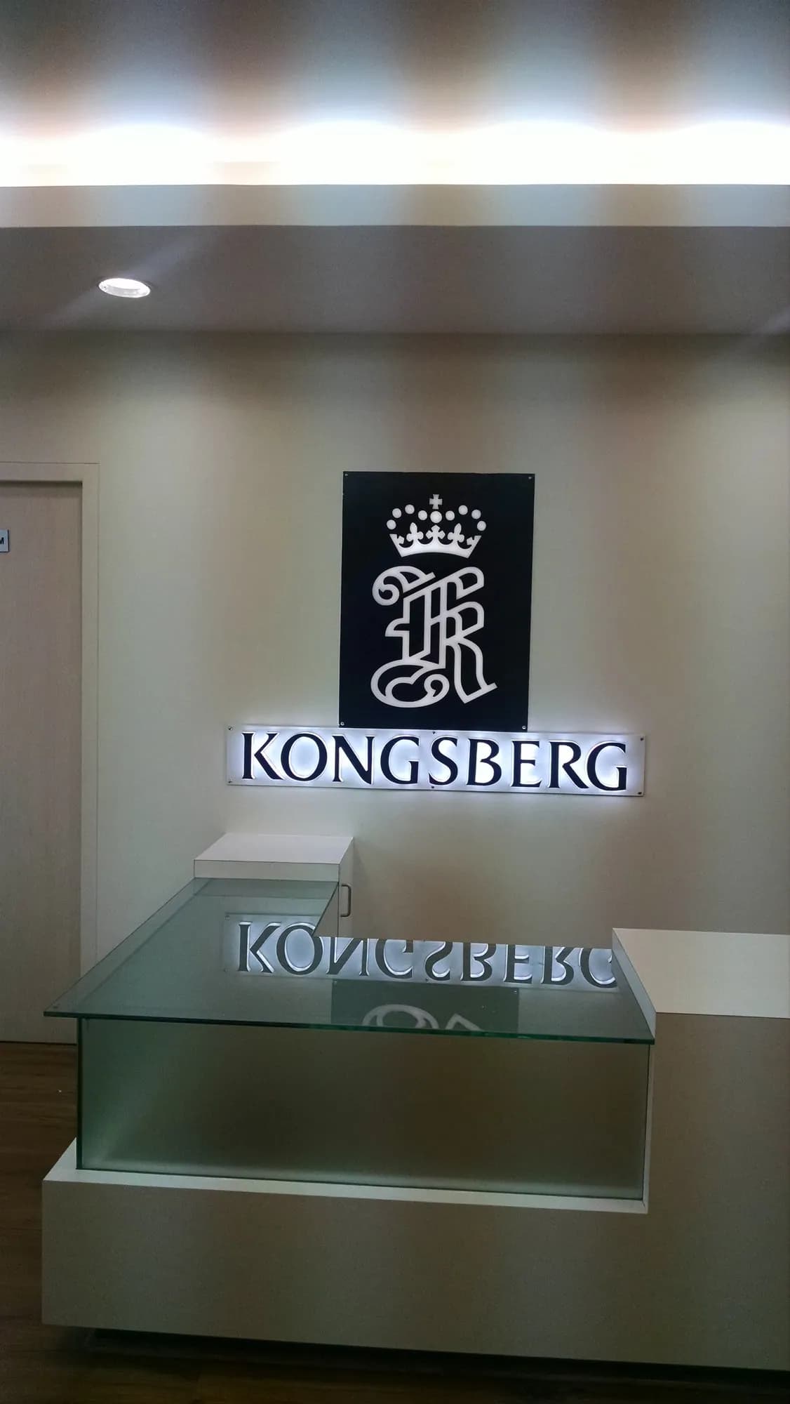 Halo-lit Kongsberg crest and letters on a reception wall