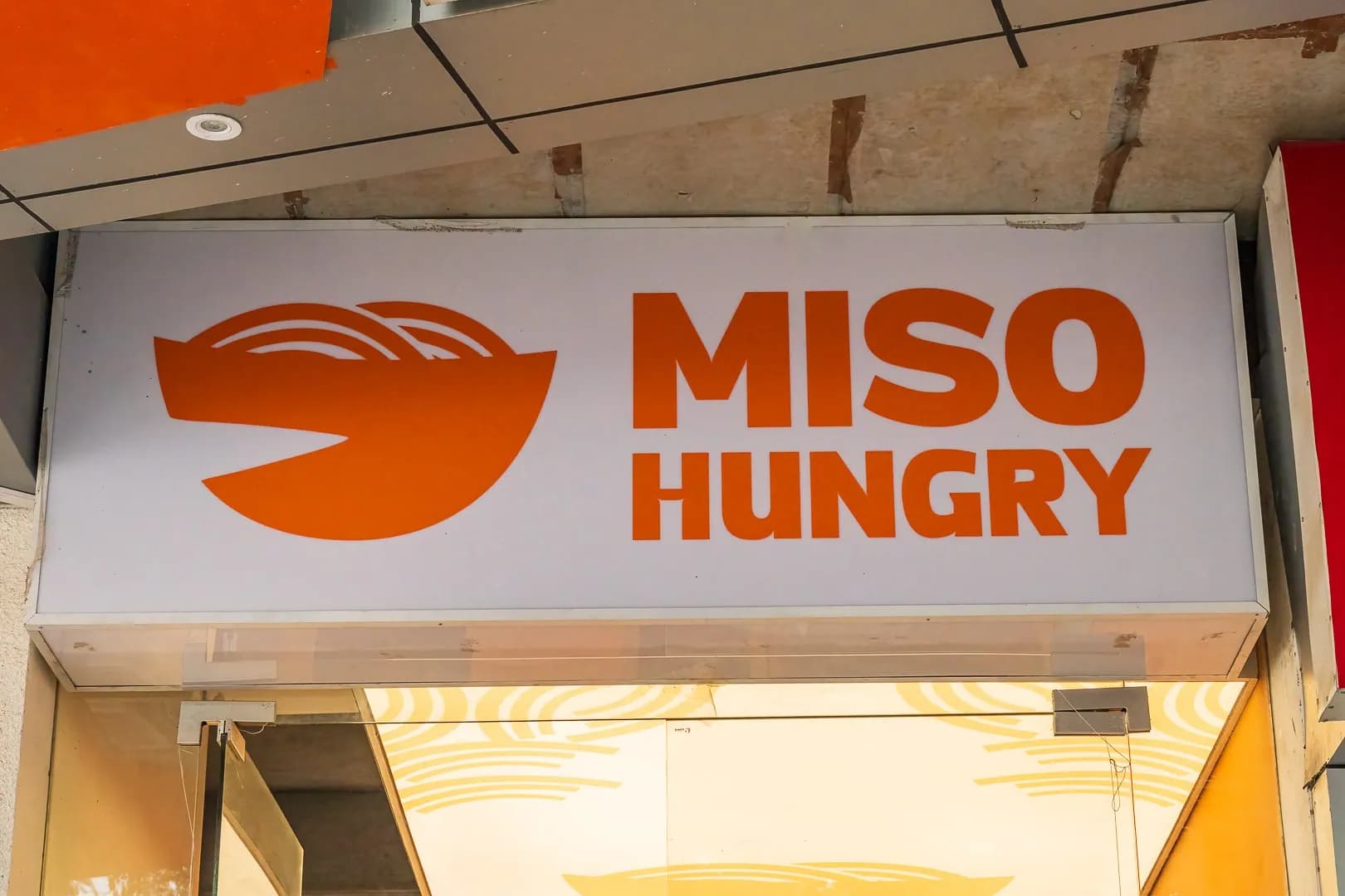 Miso Hungry illuminated box sign with the bowl logo above the entrance