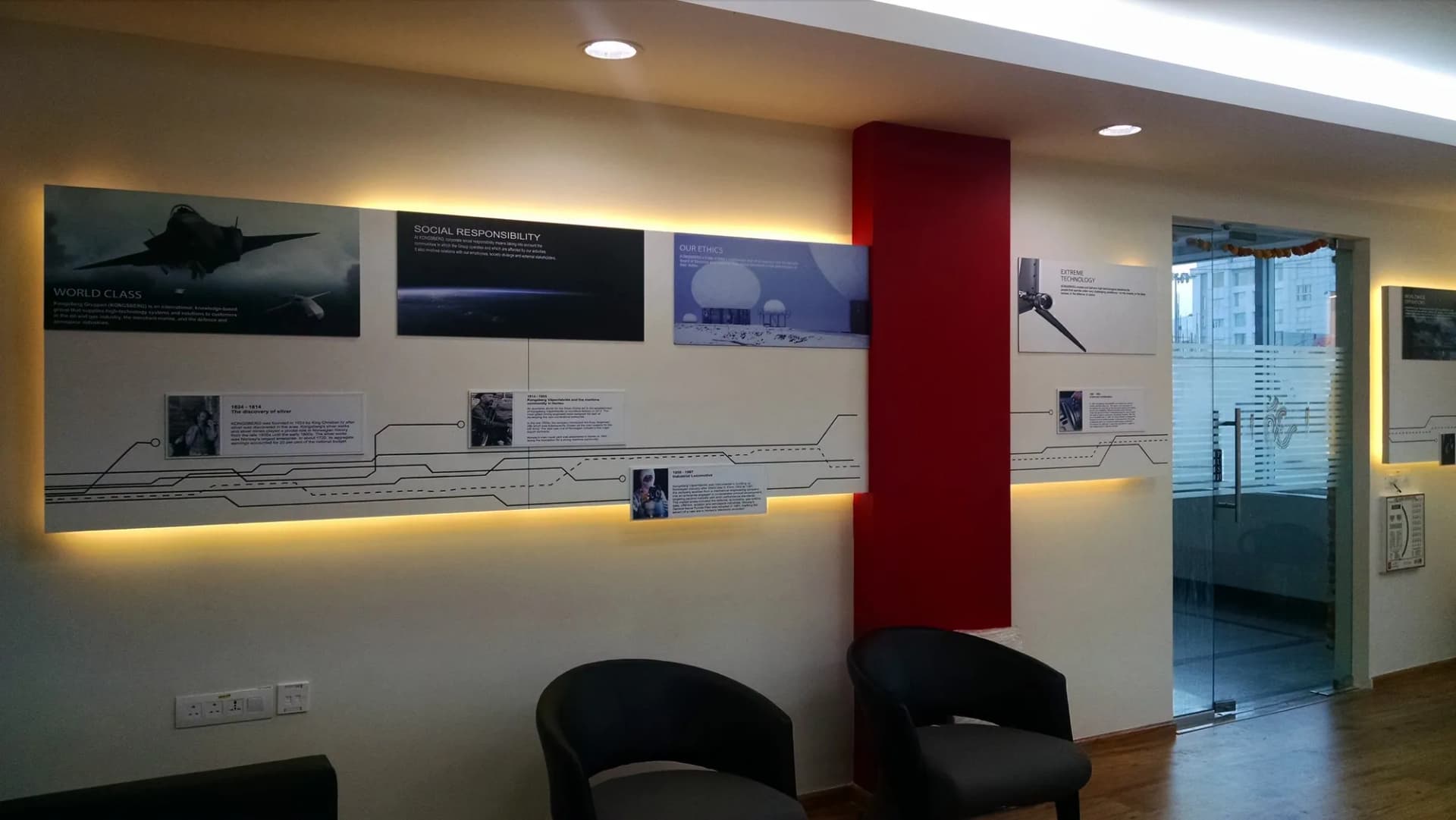 Backlit history wall with aircraft photographs and captions along an office corridor