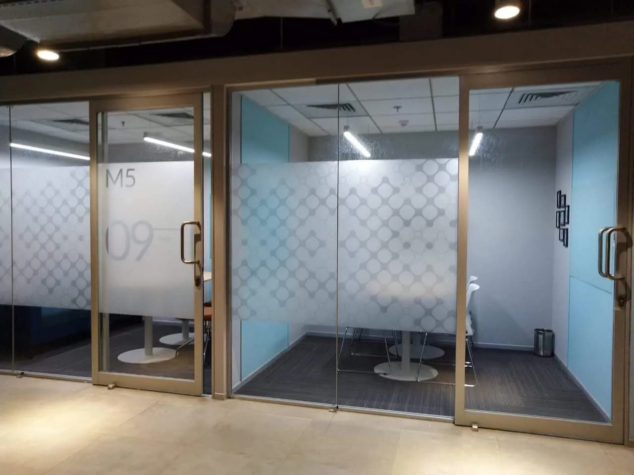 Glass meeting rooms with diamond-pattern frosted film and the room number M5 09