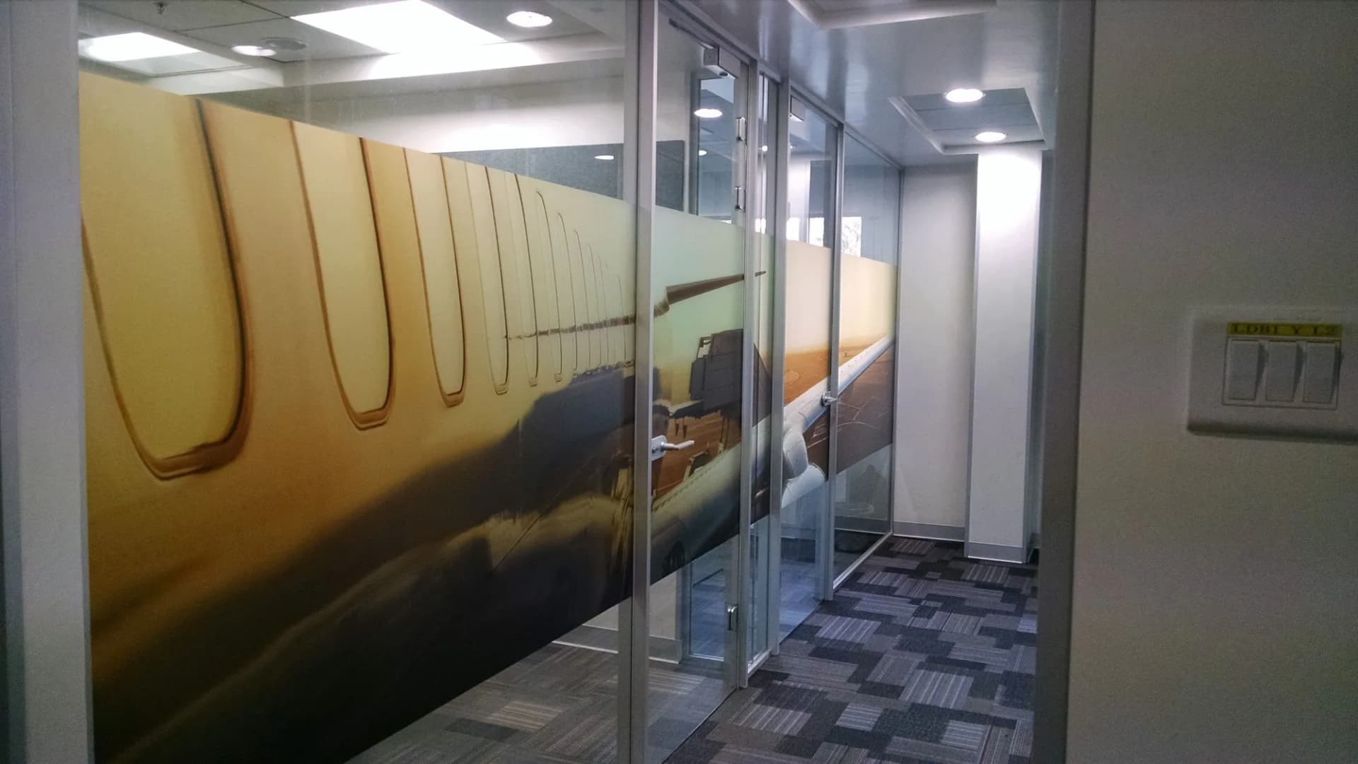 Glass partition with a printed aircraft-window and sky graphic