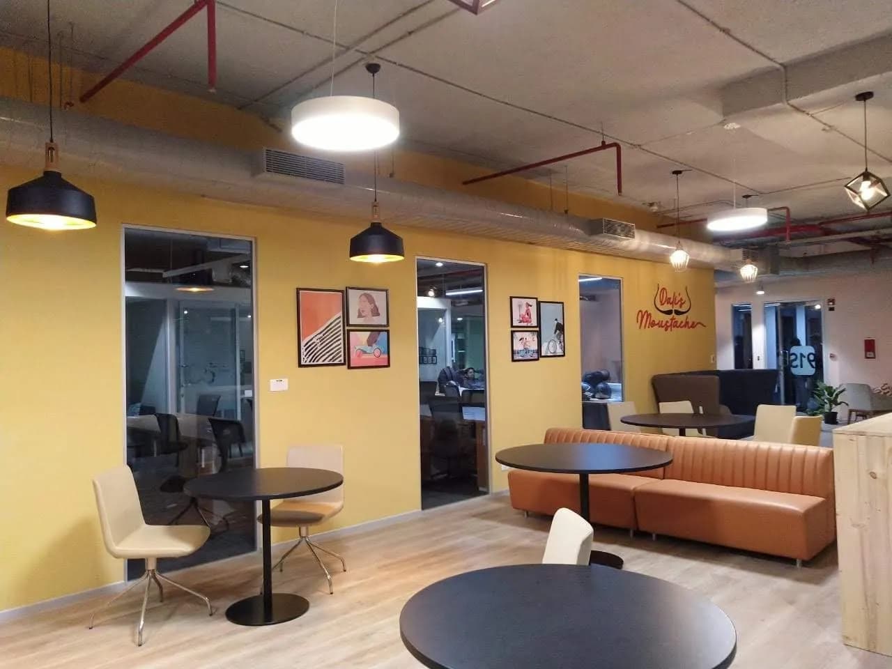 Office breakout area with framed posters on yellow walls