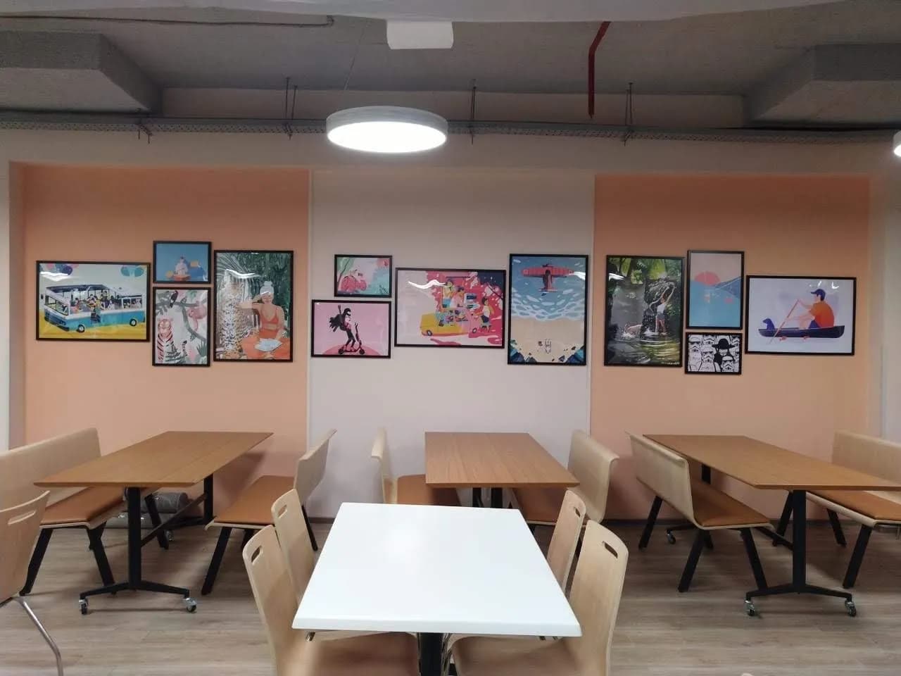 Office cafeteria with a wall of framed illustrated posters above the tables
