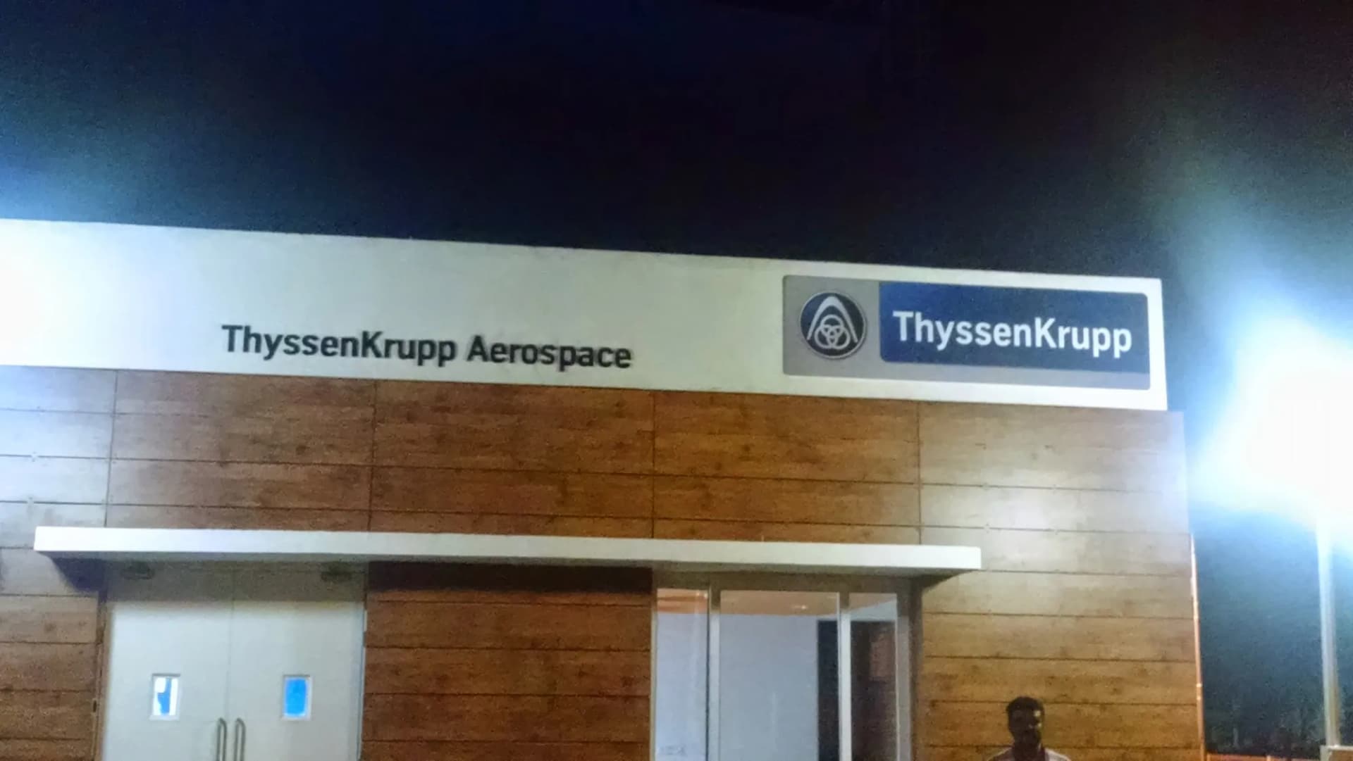 ThyssenKrupp Aerospace letters and logo panel lit at night on a building fascia