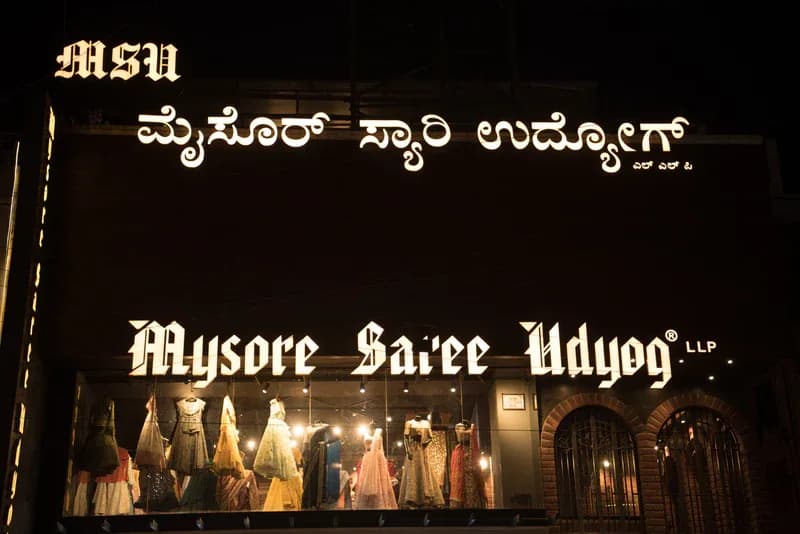 Mysore Saree Udyog storefront at night with the name in Kannada and English