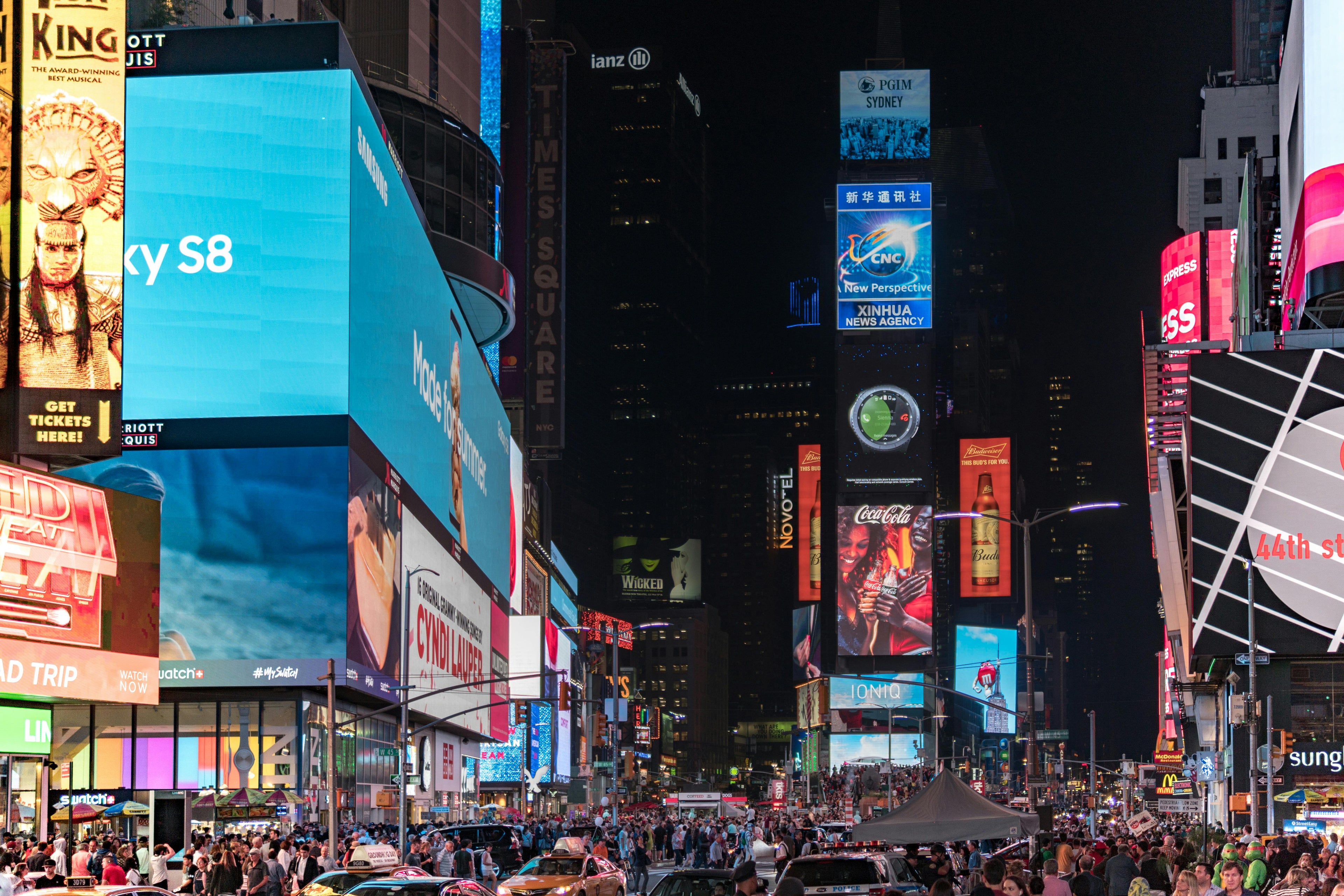 Times Square at night with bright digital billboards and a bustling crowd