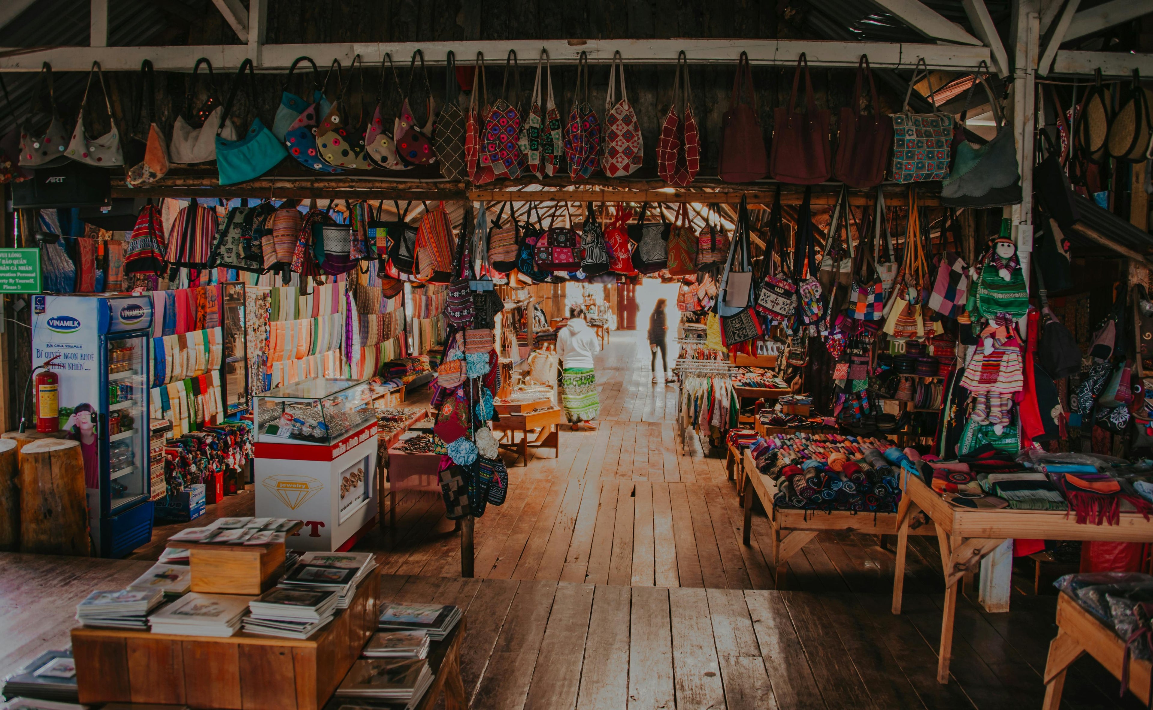 Interior of a rustic retail store with colorful handmade bags, textiles, and wooden floors